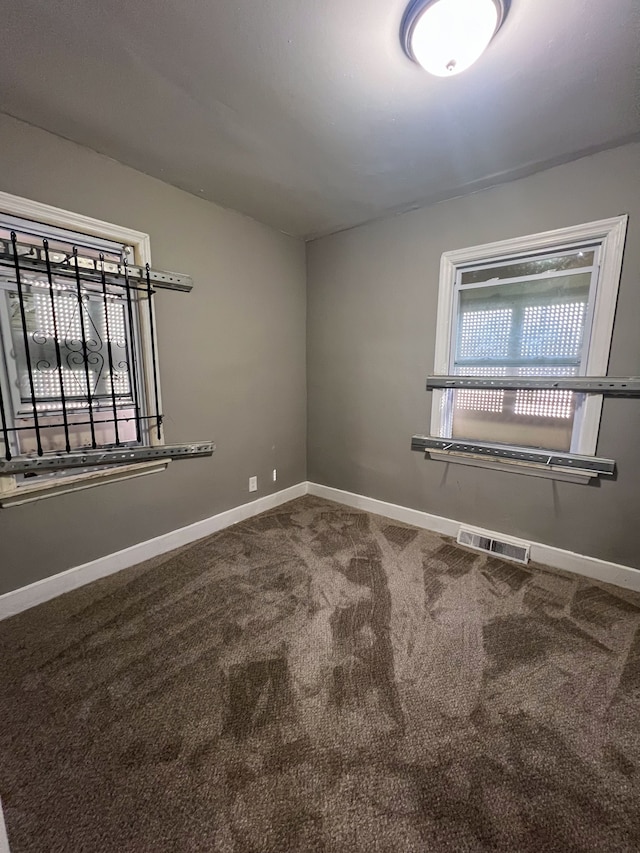 spare room featuring carpet floors, visible vents, and baseboards