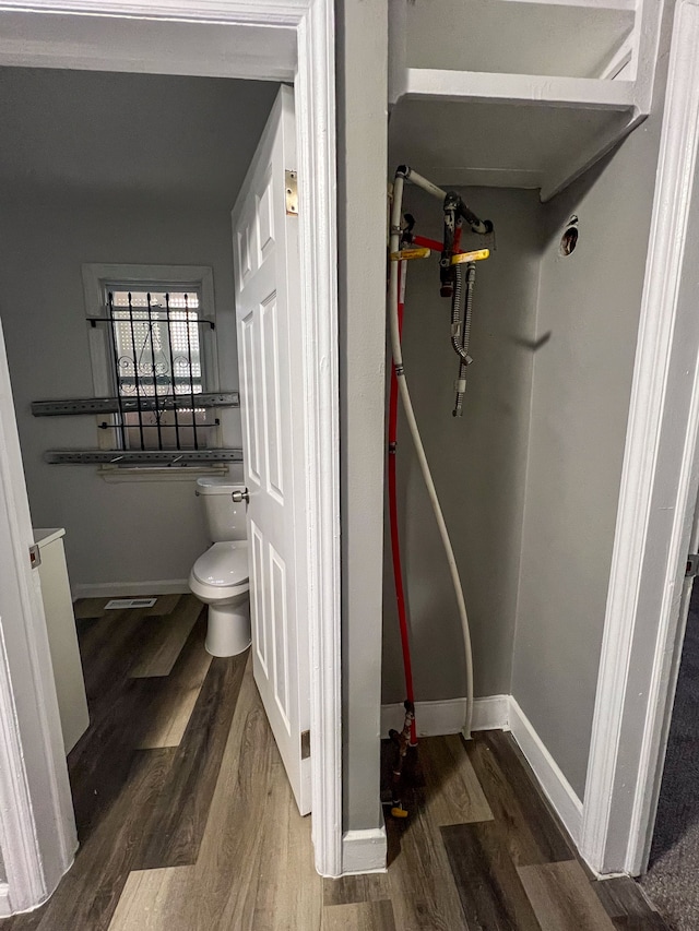 bathroom featuring toilet, visible vents, baseboards, and wood finished floors