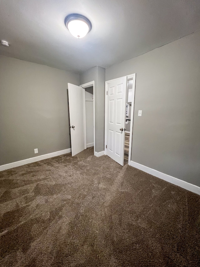 unfurnished bedroom with baseboards and dark colored carpet