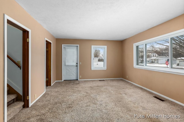 carpeted empty room with a textured ceiling