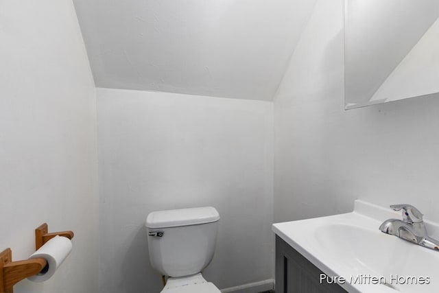 bathroom with vanity, lofted ceiling, and toilet