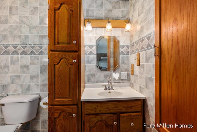 bathroom with tile walls, vanity, and toilet