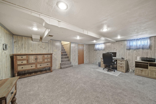 office space featuring light colored carpet, a textured ceiling, and wood walls