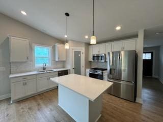 kitchen with stainless steel appliances, a sink, plenty of natural light, tasteful backsplash, and vaulted ceiling