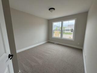 spare room featuring baseboards and carpet floors