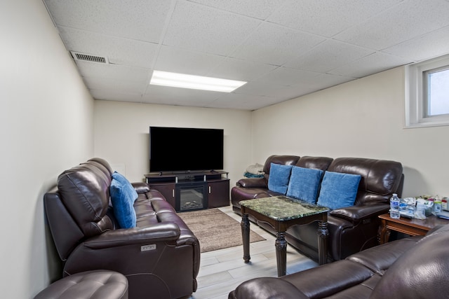 living room with light wood finished floors, a drop ceiling, and visible vents