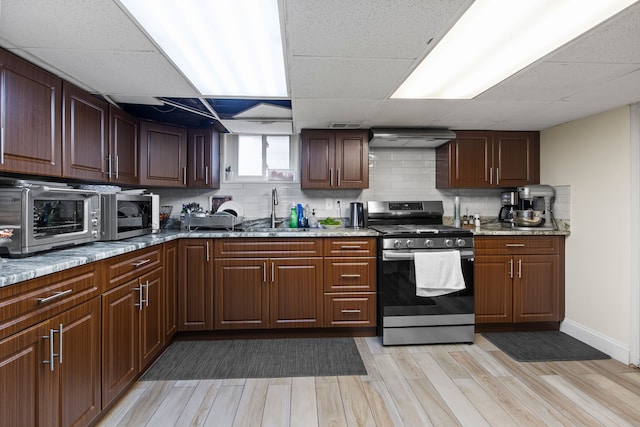 kitchen featuring stainless steel appliances, light stone counters, backsplash, and a sink