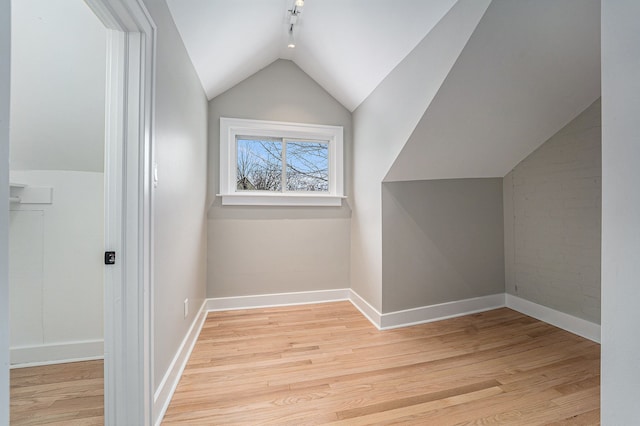 bonus room featuring light hardwood / wood-style flooring, brick wall, and lofted ceiling