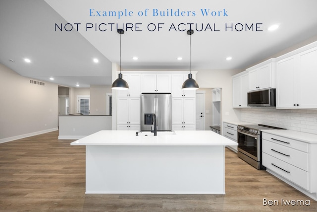 kitchen with white cabinets, hanging light fixtures, stainless steel appliances, and a kitchen island with sink