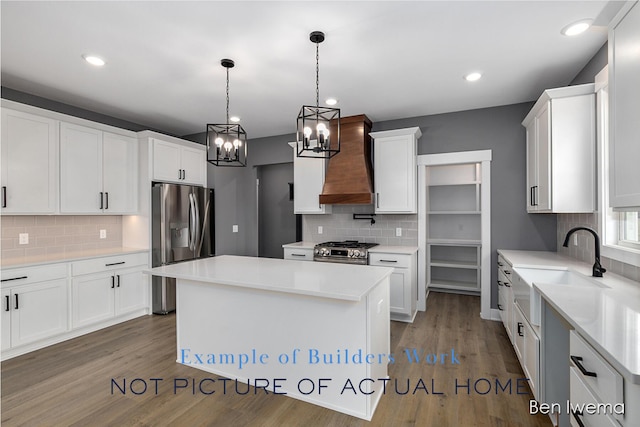 kitchen featuring premium range hood, stainless steel appliances, decorative light fixtures, a kitchen island, and white cabinetry