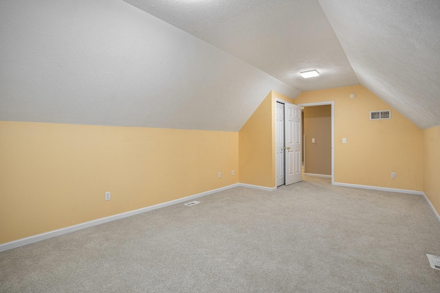 bonus room featuring light carpet, lofted ceiling, and a textured ceiling