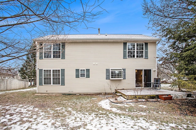 snow covered back of property with a deck