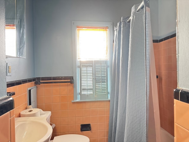 bathroom with tile walls, sink, toilet, and walk in shower