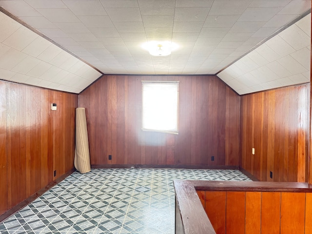 additional living space featuring lofted ceiling and wooden walls