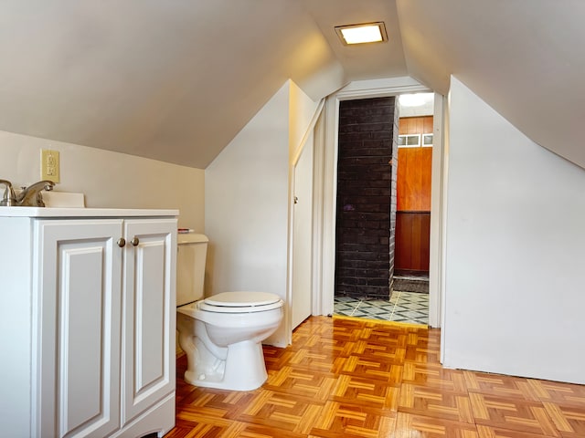 bathroom featuring parquet flooring, toilet, and lofted ceiling