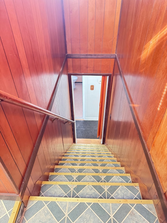 stairway featuring wooden walls