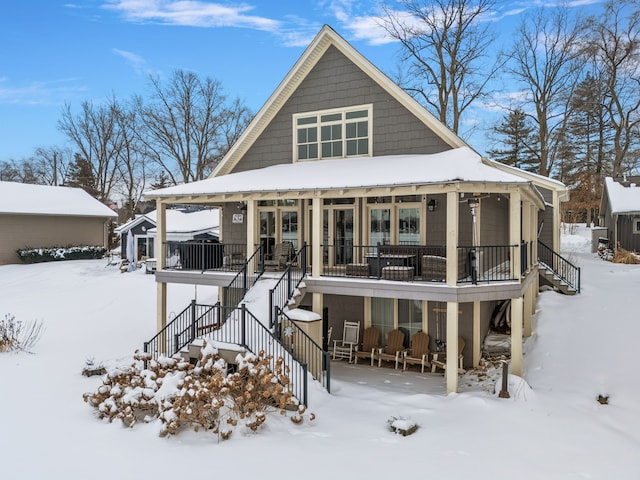 snow covered property featuring a porch and stairs