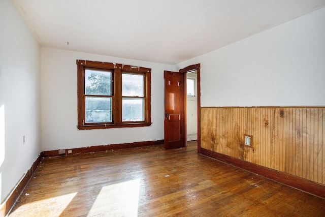 unfurnished room with dark wood-type flooring and wooden walls