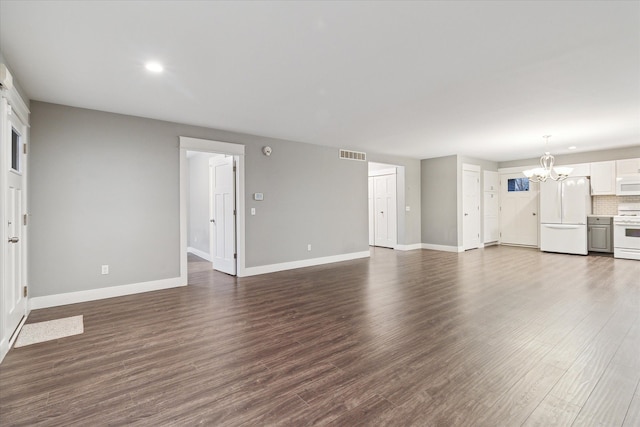 unfurnished living room featuring a chandelier and dark wood-type flooring