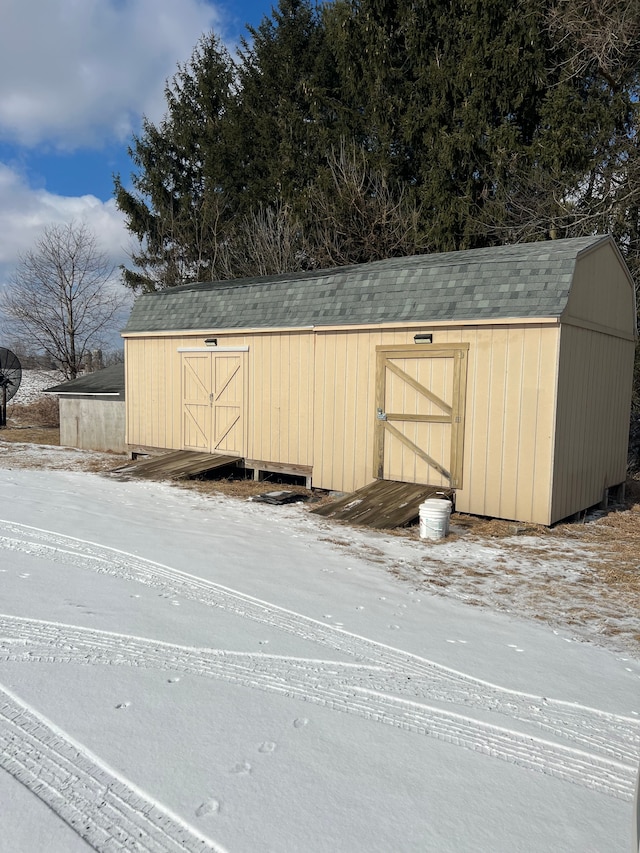 snow covered structure featuring an outbuilding