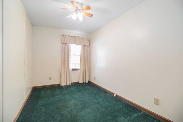 spare room featuring ceiling fan, dark colored carpet, and baseboards