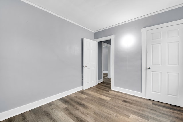 unfurnished bedroom featuring baseboards, wood finished floors, and crown molding