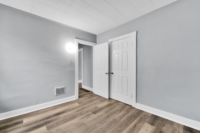 unfurnished bedroom featuring visible vents, baseboards, and wood finished floors