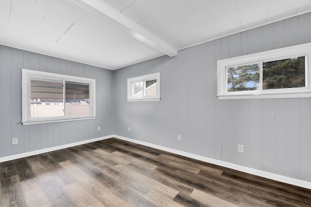 spare room with dark wood-style floors, beamed ceiling, and baseboards