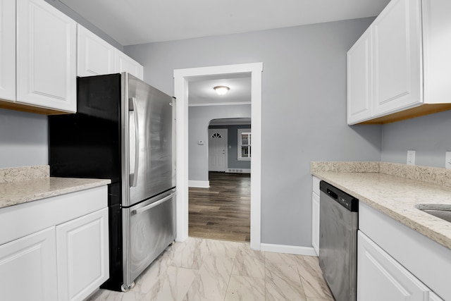 kitchen with light stone countertops, marble finish floor, appliances with stainless steel finishes, and white cabinets