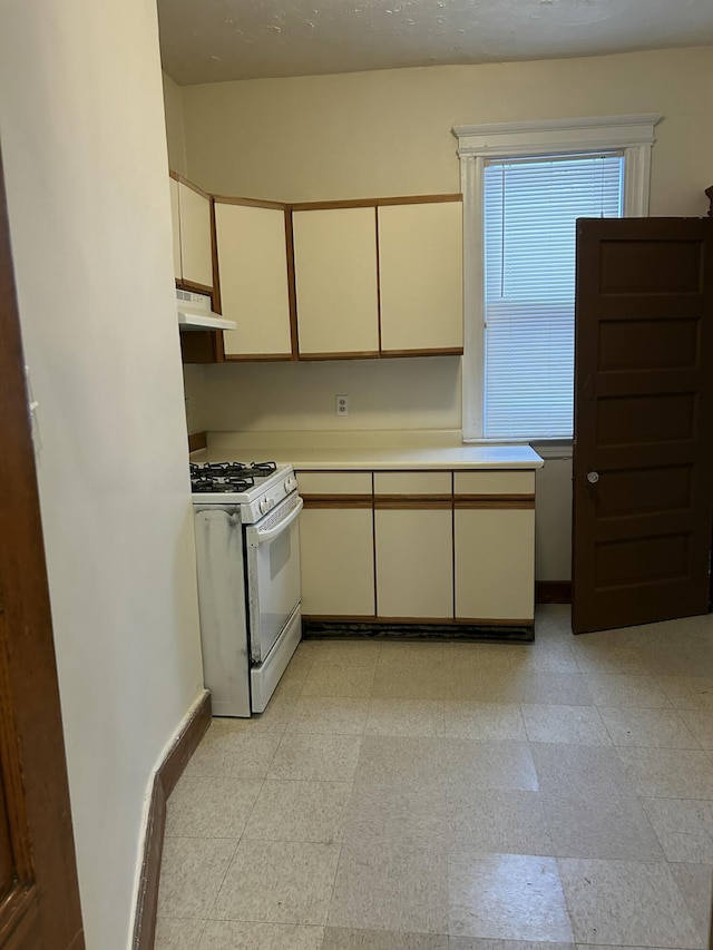 kitchen featuring white range with gas stovetop and cream cabinetry