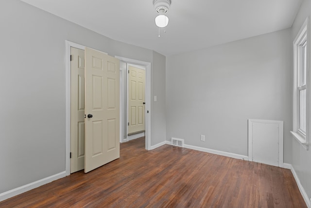 spare room with a wealth of natural light and dark wood-type flooring