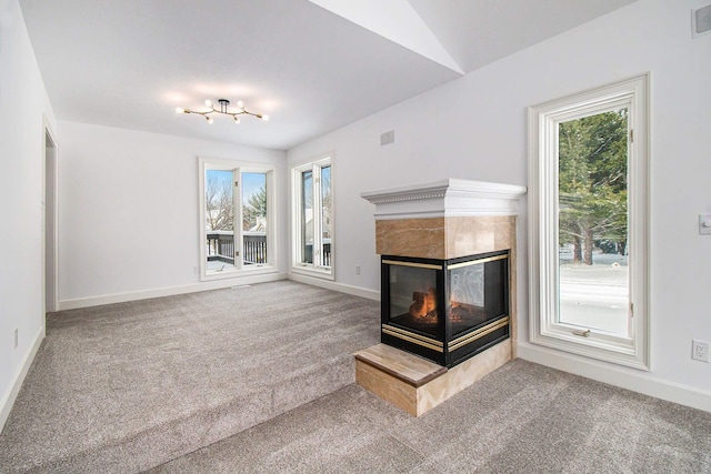 unfurnished living room with a tiled fireplace, carpet floors, and lofted ceiling