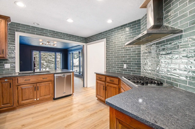 kitchen with light hardwood / wood-style flooring, wall chimney exhaust hood, stainless steel appliances, decorative backsplash, and sink