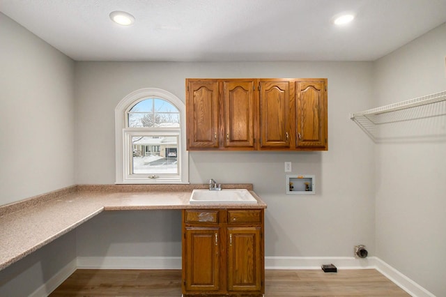 washroom featuring washer hookup, cabinets, sink, and light hardwood / wood-style floors