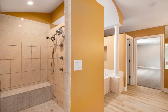 bathroom featuring a tile shower, decorative columns, and wood-type flooring