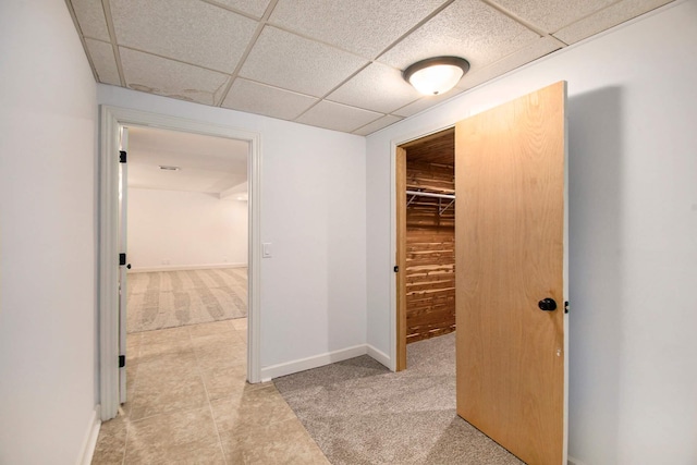 hall with a paneled ceiling and light carpet