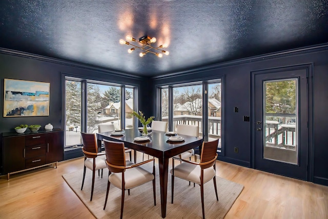 dining room featuring light hardwood / wood-style floors, a chandelier, crown molding, and a textured ceiling