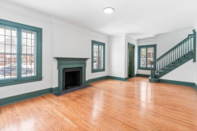 unfurnished living room featuring a fireplace, a wealth of natural light, and hardwood / wood-style floors