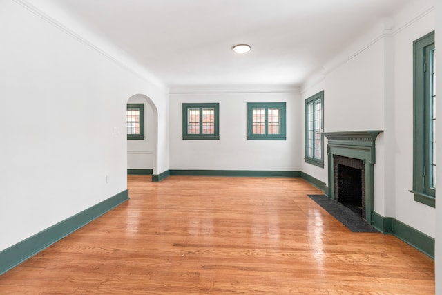 unfurnished living room with light wood-type flooring and ornamental molding