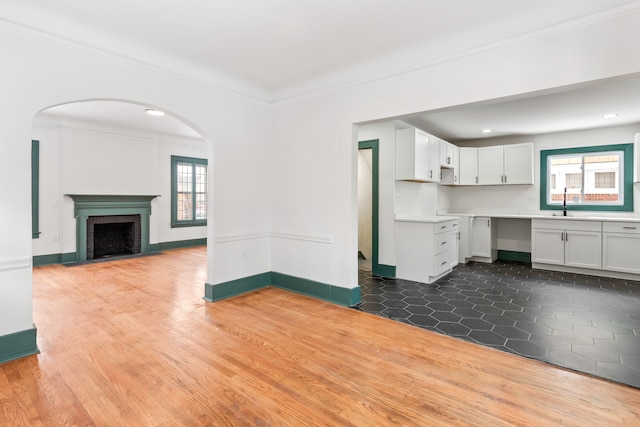 unfurnished living room featuring a fireplace, hardwood / wood-style flooring, ornamental molding, and a healthy amount of sunlight