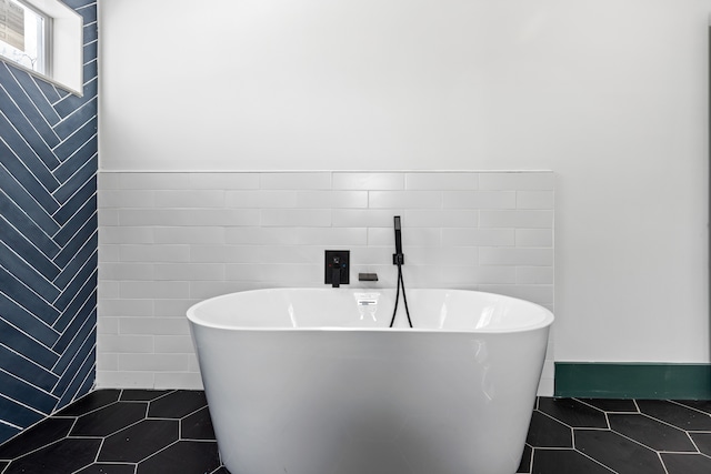 bathroom with a washtub, tile patterned floors, and tile walls