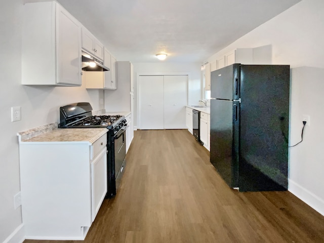 kitchen featuring sink, black appliances, white cabinets, and hardwood / wood-style floors