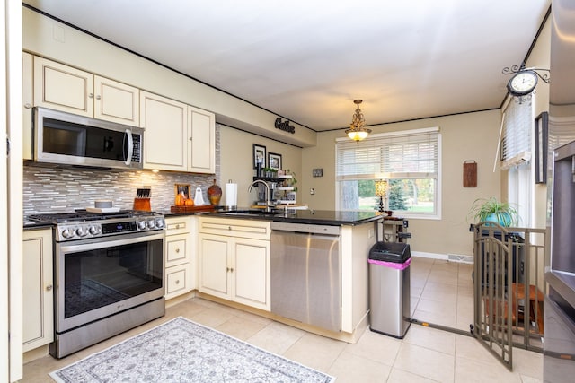 kitchen with kitchen peninsula, cream cabinets, stainless steel appliances, sink, and decorative backsplash