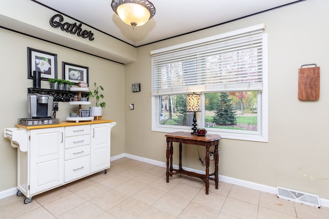 interior space with wood counters, light tile patterned floors, and white cabinets