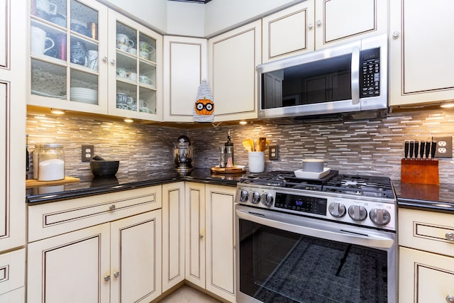 kitchen with appliances with stainless steel finishes, cream cabinets, and backsplash