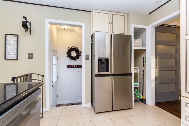 kitchen featuring appliances with stainless steel finishes, a barn door, and light tile patterned floors