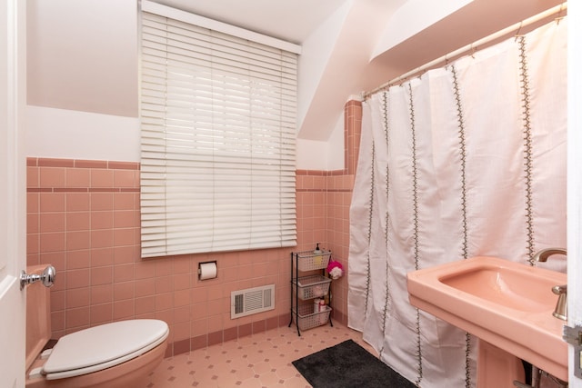 bathroom featuring sink, tile walls, and toilet