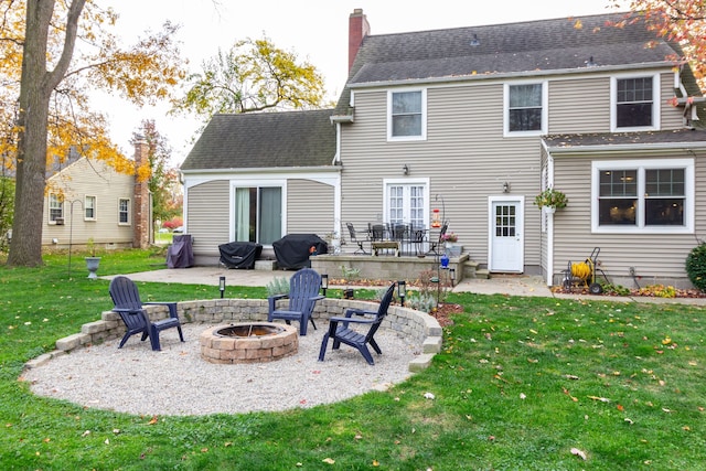 back of property with an outdoor fire pit, a lawn, and a patio area