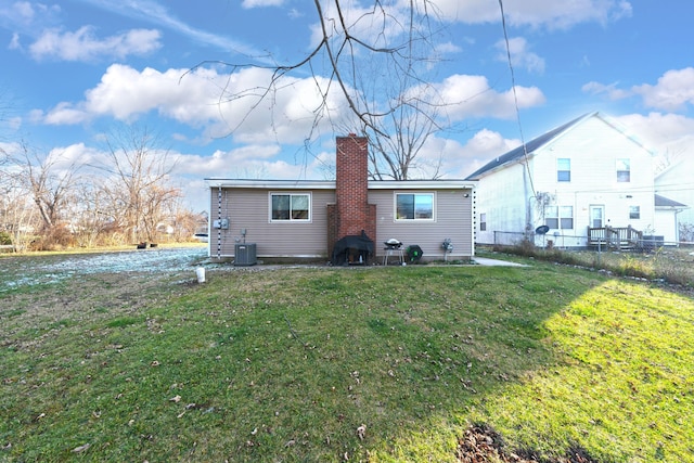 back of property with a lawn and central AC