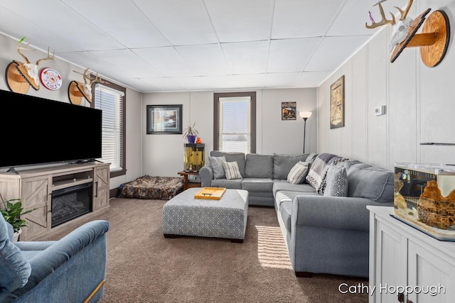 living room featuring dark carpet and a drop ceiling